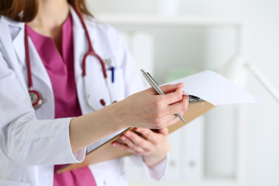 Female medicine doctor hand holding silver pen looking in clipboard pad closeup. Ward round, patient visit check, 911, medical calculation and statistics concept. Physician ready to examine patient