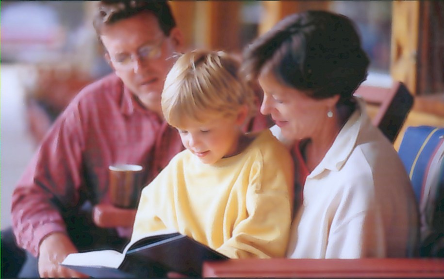 Still from the NALA video. 2 parents reading a book with their child