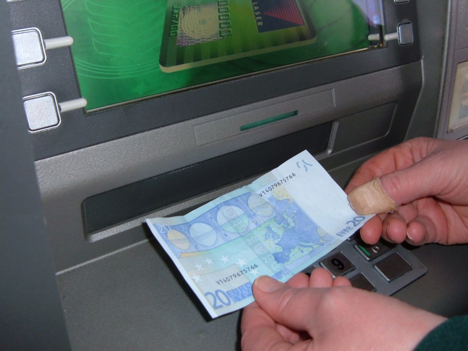 ATM cash machine. Somebody's hands withdrawing money