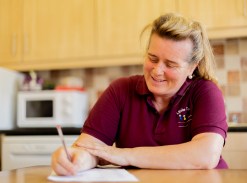 Woman in the kitchen reads a workbook