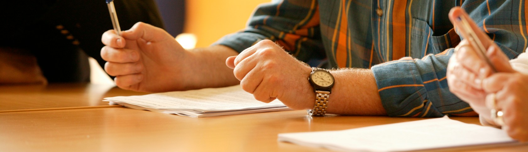 people sitting at a table with hands on the table and a paper