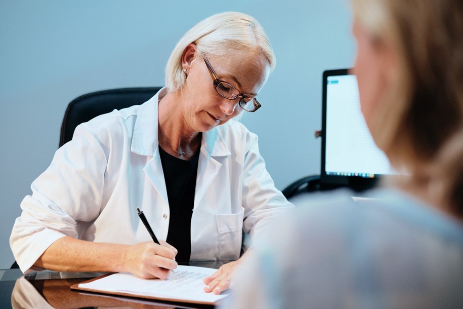 A GP writing a prescription to a patient