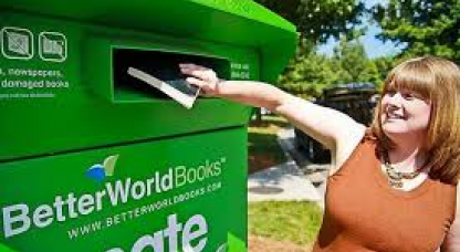 A woman posts a package into the green post box