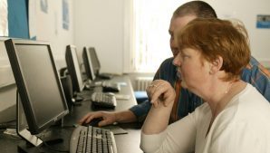 Two adult students in front of a Desktop PC