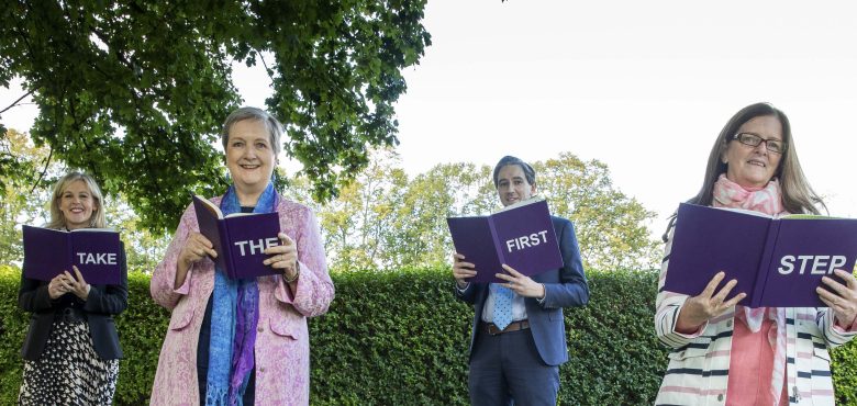 Four people spelling out 'Take the First Step' with books