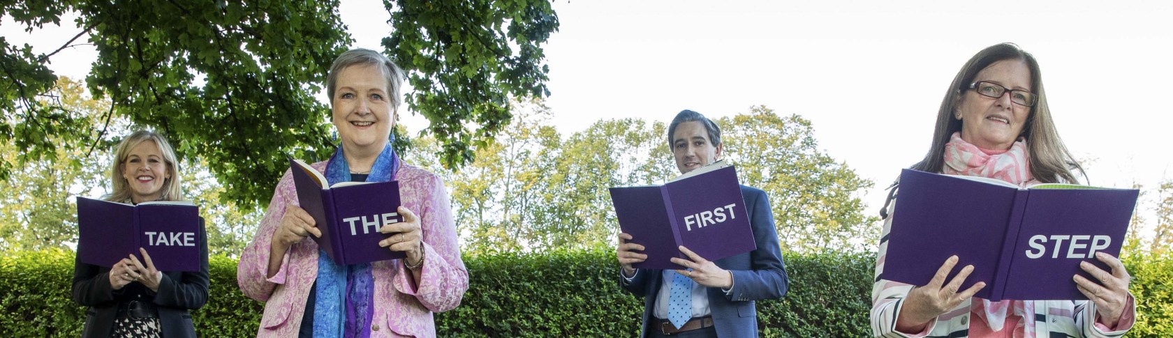 Four people spelling out 'Take the First Step' with books