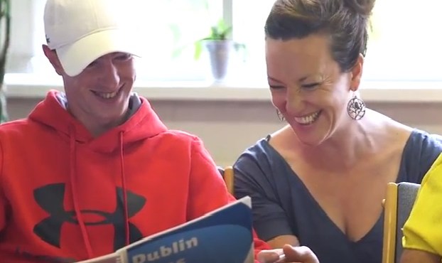 2 people smiling while reading a book