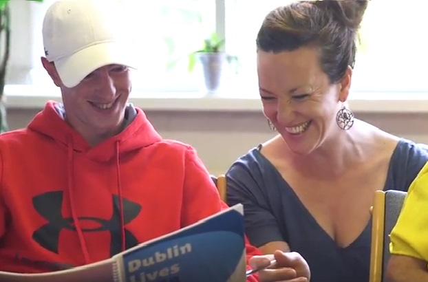 2 people smiling while reading a book