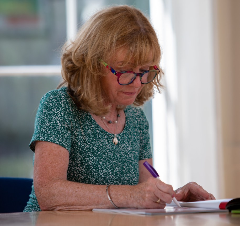 Woman sit at at table writing in a workbook