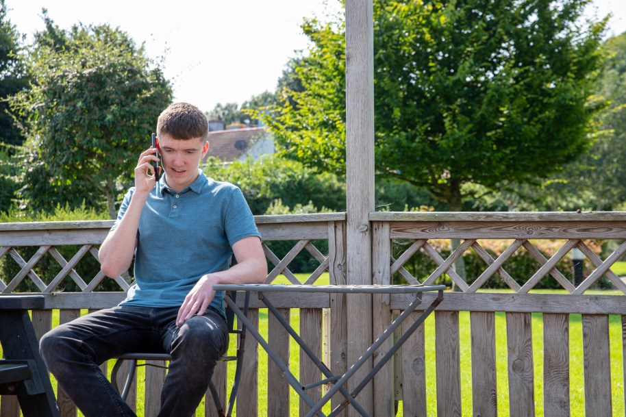 Man seated on a patio in the garden talking on mobile phone